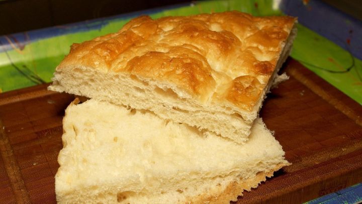 Fladenbrot liegt auf einem Holzbrett, frisch gebacken, mit einer goldbraunen, knusprigen Oberseite.