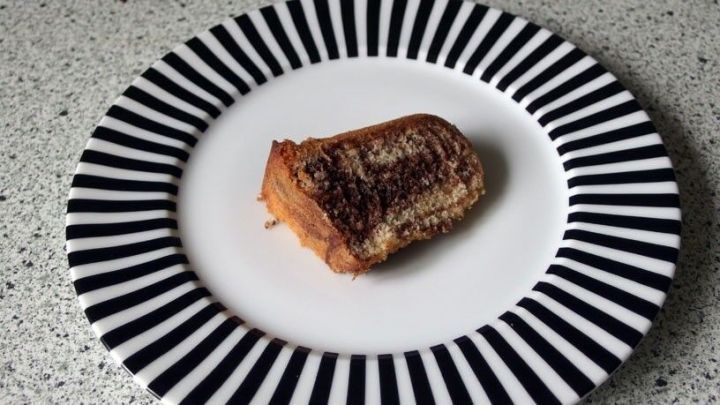 Ein St&uuml;ck Marmorkuchen liegt auf einem schwarz-wei&szlig;en Teller und zeigt eine helle und dunkle Marmorierung im Geb&auml;ck.