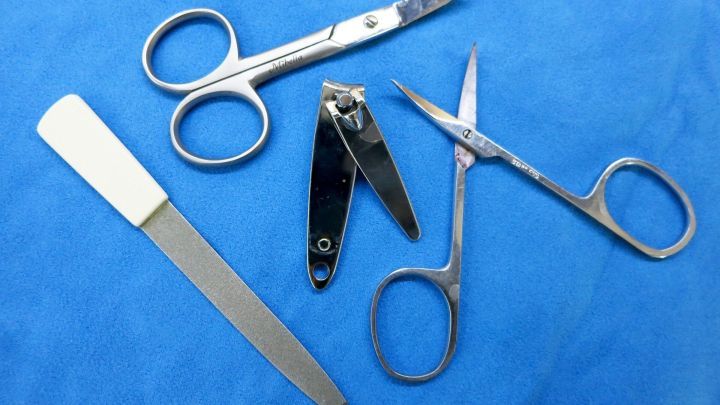 Nagelscheren und andere Manik&uuml;re-Werkzeuge liegen auf blauer Unterlage, bereit zur Desinfektion mit einem Vaporisator.