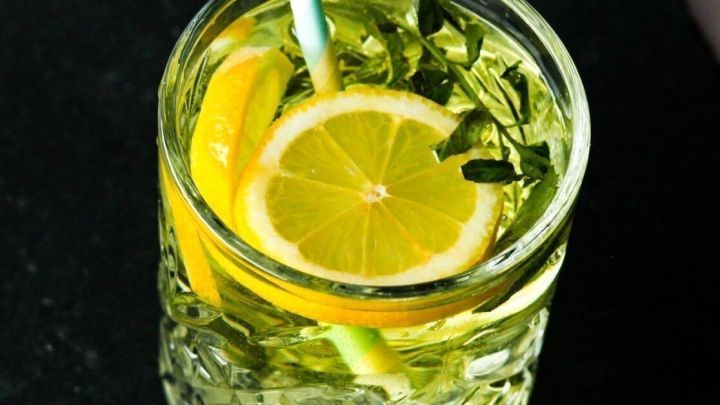 Ein Cocktail mit frischem Zitronenscheiben und einem Strohhalm ist auf einem dunklen Untergrund platziert.
