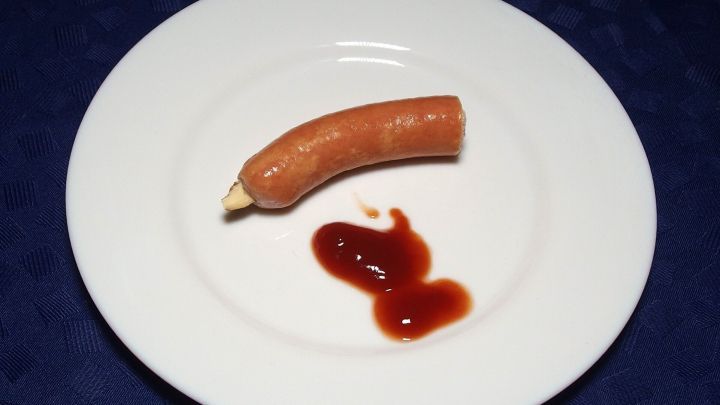 Ein auf einem Teller liegender Wurstfinger mit Ketchup, der auf den ersten Blick wie ein abgehackter Finger aussieht.