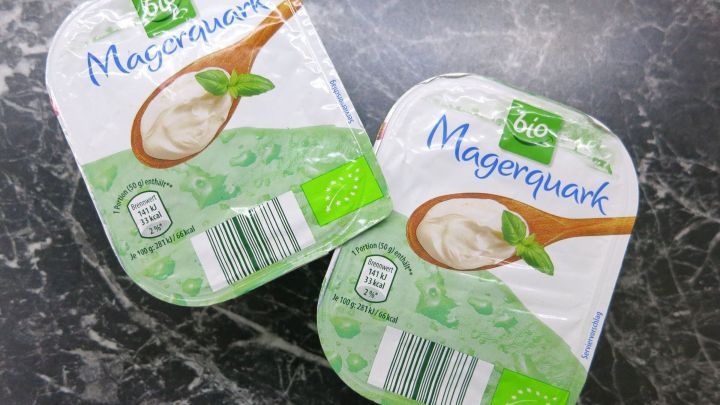 Zwei Packungen Magerquark liegen auf einer dunklen, marmorierten Oberfl&auml;che, bereit zur Anwendung gegen Schwellungen.