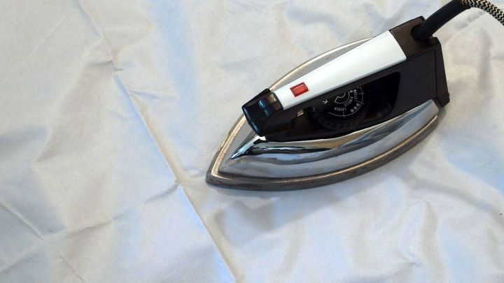 Ein Dampfb&uuml;geleisen gl&auml;ttet eine wei&szlig;e Tischdecke, um sie faltenfrei und bereit f&uuml;r den Einsatz zu machen.