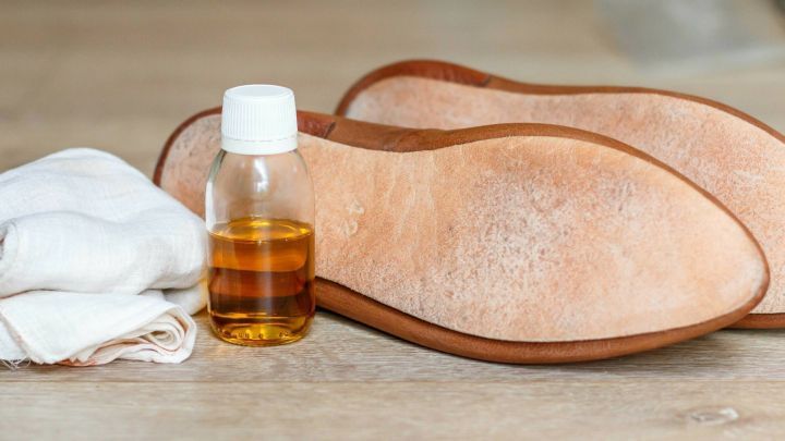 Lederschuhsohlen liegen auf einem Tisch, w&auml;hrend Lein&ouml;l-Firnis und ein Tuch daneben bereitstehen.