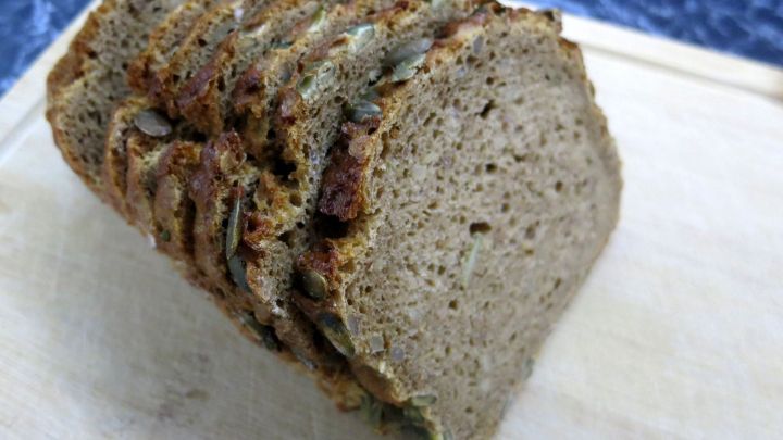 Vollkornbrot liegt auf einem Holzbrett, die Scheiben sind leicht angeschnitten und zeigen die dichte Textur und die K&ouml;rner.