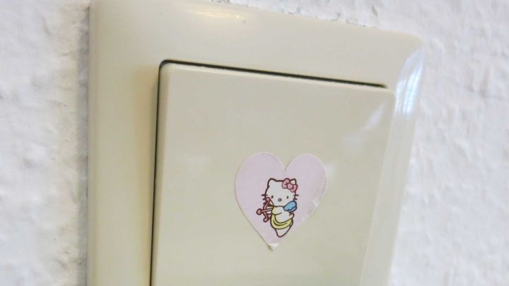 Ein Schalter mit einem Hello Kitty-Aufkleber, der dekorativ an einer wei&szlig;en Wand platziert ist.