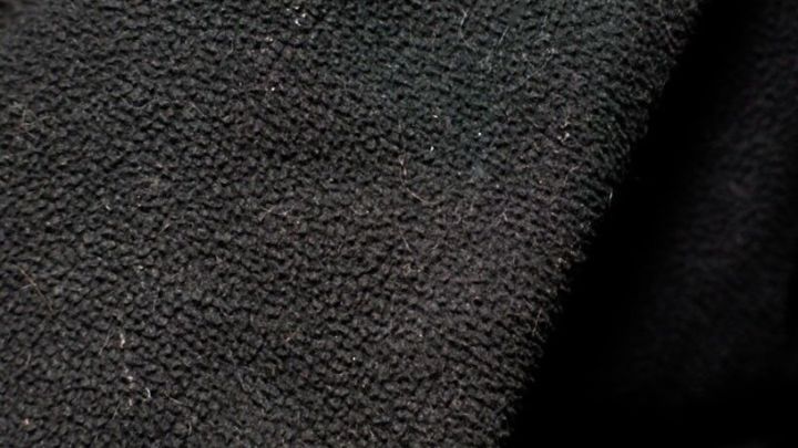 Schwarze Socken liegen auf einem wolligen Stoff, zeigen eine glatte Textur ohne sichtbare Flusen im Nahaufnahme-Kontext.