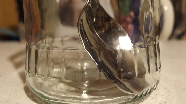 Ein Marmeladenglas steht auf einer Oberfl&auml;che, w&auml;hrend ein L&ouml;ffel darin platziert ist, um das Platzen beim Bef&uuml;llen zu verhindern.