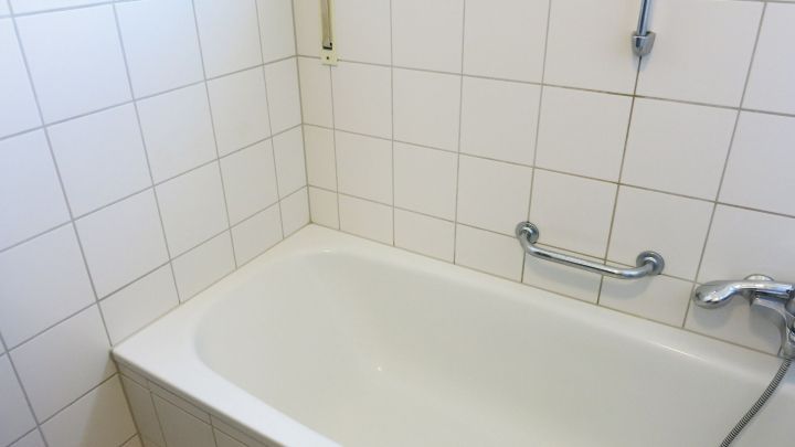 Eine saubere Badewanne steht in einem gefliessten Badezimmer, bereit f&uuml;r die n&auml;chste Nutzung nach dem Badreinigen.