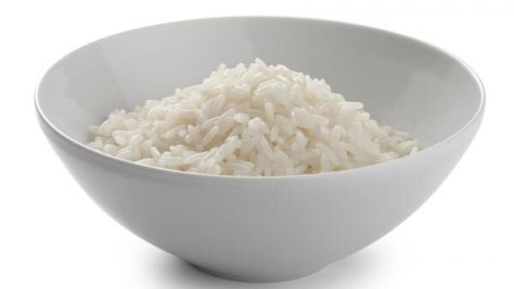 Ein Sch&uuml;ssel voller gekochtem Reis steht auf einem wei&szlig;en Hintergrund, bereit zum Servieren oder f&uuml;r eine Mahlzeit.