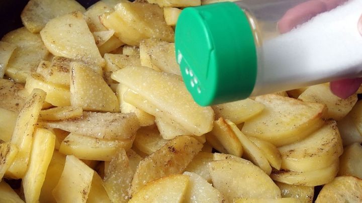 Knusprige Bratkartoffeln werden in einer Pfanne zubereitet, w&auml;hrend Salz &uuml;ber die goldbraun gebratenen Kartoffelst&uuml;cke gestreut wird.