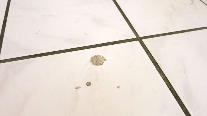 Ein Fleck auf einem hellen Fliesenboden, der gereinigt werden muss, um Edelstahl-Reiniger zu verwenden.