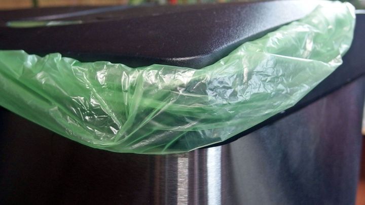 Ein schwarzer Beh&auml;lter mit einem gr&uuml;nen M&uuml;llbeutel, der zur Abwehr von Motten in einer Umgebung bereitsteht.