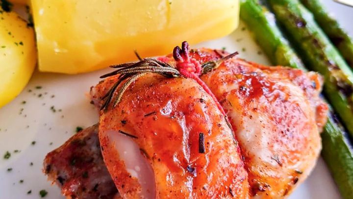 Zarte Putenrouladen liegen auf dem Teller, umgeben von Kartoffeln und gr&uuml;nem Spargel, liebevoll garniert.