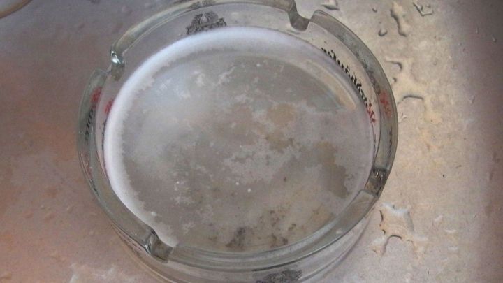 Ein Aschenbecher liegt im Wasser eines Sp&uuml;lbeckens und wird gerade gereinigt, um wieder sauber wie neu zu sein.