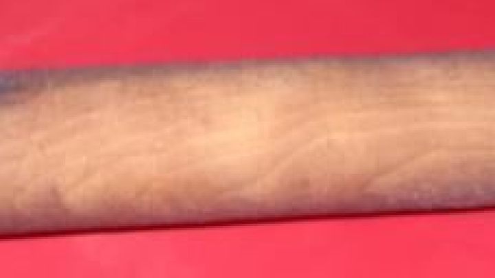 Ein Nudelholz mit &Uuml;berzug liegt auf einem roten Untergrund, um Teig ausrollen ohne Ankleben zu erleichtern.