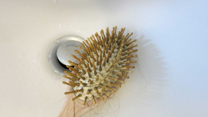 Eine Haarb&uuml;rste mit Haaren liegt in einem Waschbecken, bereit zur Anwendung von "Abflussfrei", um Haare zu entfernen.