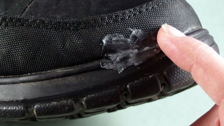 Ein Schuh mit einer abgedichteten Naht wird mit einem Finger ber&uuml;hrt, um die Impr&auml;gnierung zu &uuml;berpr&uuml;fen.