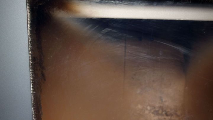 Ein beschlagener Glasbereich zeigt Ru&szlig;flecken, die mit einem Fettl&ouml;ser-Spray behandelt werden sollen, um sie zu entfernen.