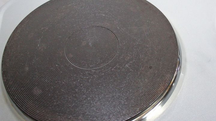 Ein schmutziger Herd mit festgebackenem Zucker wird mit Sp&uuml;lmittel gereinigt, um die Oberfl&auml;che wieder sauber zu machen.