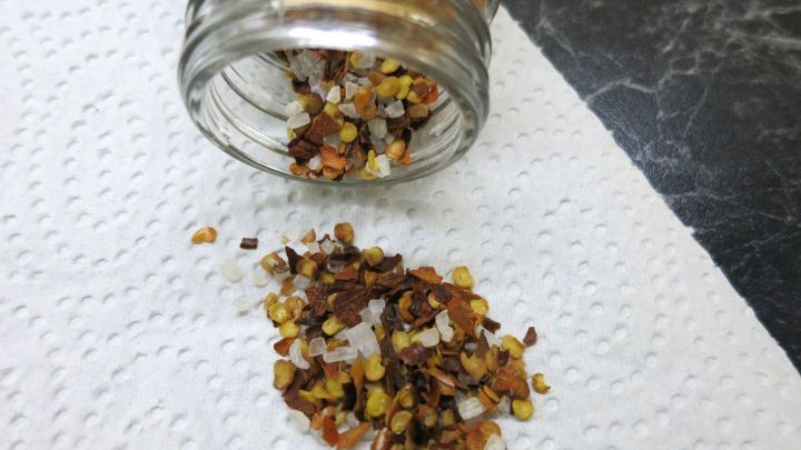 Ein Glas mit Chili-Salz liegt auf einem Papiertuch, w&auml;hrend der Inhalt chaotisch verstreut ist.