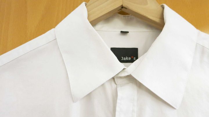 Ein Hemd h&auml;ngt an einem Holzkleiderb&uuml;gel und ist zur Minimierung des B&uuml;gelaufwands mit Gewichten beschwert.