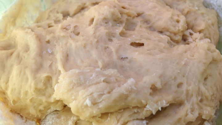 Ein Hefeteig wird in einer Sch&uuml;ssel geknetet, um eine luftige, lockere Konsistenz zu erreichen, bereit zum Backen.