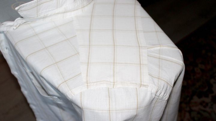 Ein geb&uuml;geltes Hemd liegt ordentlich auf einem B&uuml;gelbrett, umgeben von einem ruhigen, h&auml;uslichen Hintergrund.