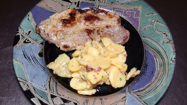 Eine farbenfrohe Telleranordnung zeigt knusprige Bratkartoffeln und ein gegrilltes St&uuml;ck Fleisch, appetitlich angerichtet.