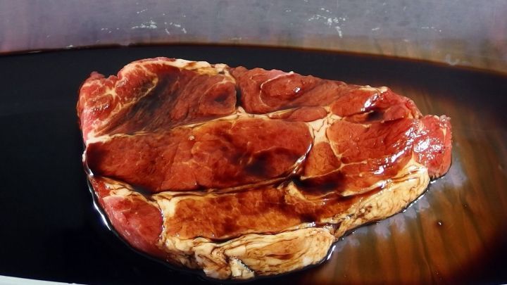 Rohes Fleisch liegt in einer Sch&uuml;ssel mit Sojaso&szlig;e, mariniert zur Zartmachung und kr&auml;ftigen Geschmacksverst&auml;rkung.