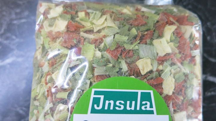 Eine transparente Packung mit getrocknetem Suppengr&uuml;n zeigt farbenfrohe Kr&auml;uter und Gem&uuml;se, bereit zur Verwendung in der K&uuml;che.