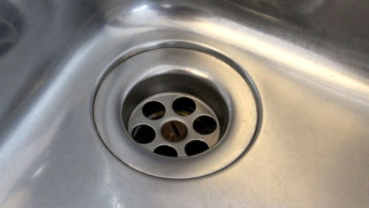 Ein Abfluss sitzt in einer Edelstahlsp&uuml;le, vorbereitet f&uuml;r den Einsatz eines Nass-Saugers zur Vermeidung von Verstopfungen.