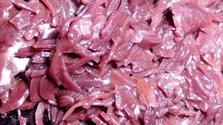 Zerkleinertes Rotkohl liegt auf einer dunklen Unterlage, bereit zur Zubereitung eines herzhaften Gerichts.