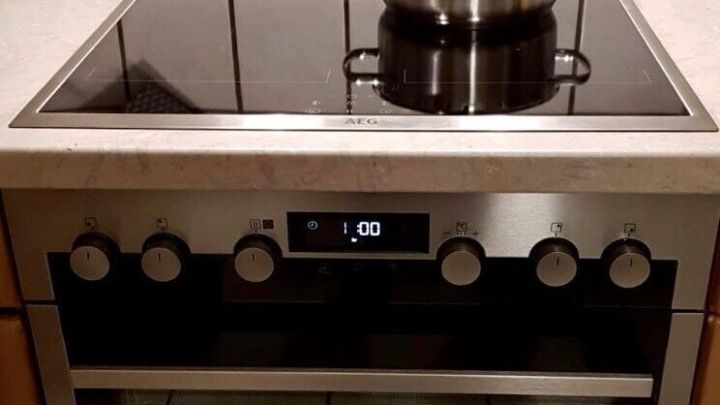 Das induktionskochfeld ist sauber, w&auml;hrend ein Kochtopf darauf steht, und ein moderner Backofen darunter ist sichtbar.