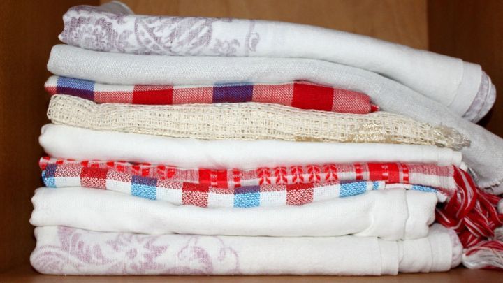 Gestapelte Tischdecken liegen ordentlich im Schrank und zeigen eine Mischung aus gemusterten und einfarbigen Designs.