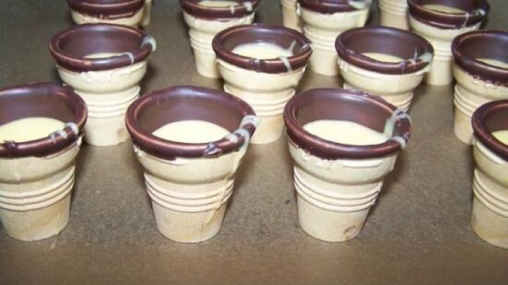 Kleine Waffelbecher stehen ordentlich auf einer Tischplatte, bereit f&uuml;r das F&uuml;llen mit leckerem Kuchenteig.