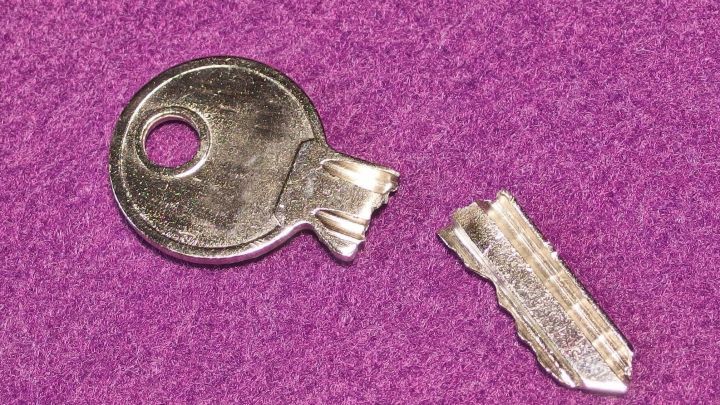 Ein abgebrochener Schl&uuml;ssel liegt neben dem restlichen Schl&uuml;sselk&ouml;rper auf einem lila Hintergrund.