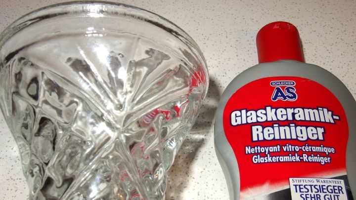Ein Glasvase steht neben einer Flasche Glaskeramik-Reiniger, um Kalk und Dreck zu entfernen.