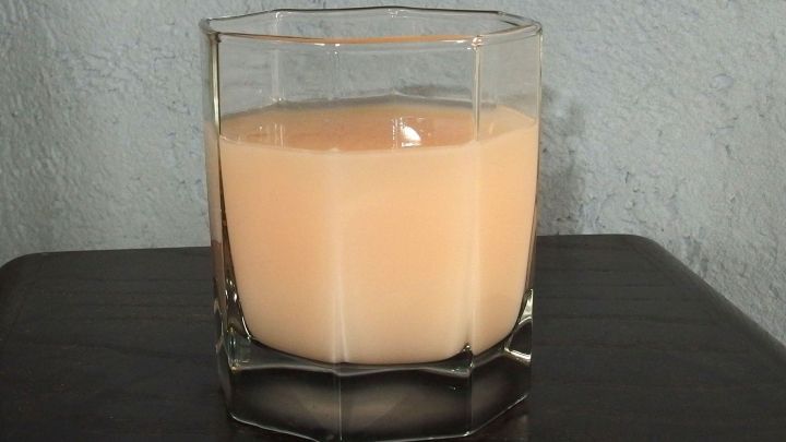 Ein Glas Wodka mit Kr&uuml;meltee steht auf einem dunklen Tisch, umgeben von einer schlichten Wand, leicht tr&uuml;b und beige.