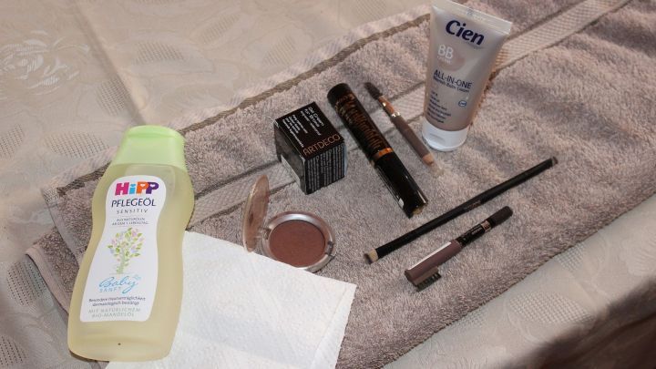 Auf einem Handtuch liegen verschiedene Kosmetikprodukte, darunter Baby&ouml;l, Feuchtigkeitscreme und Make-up.