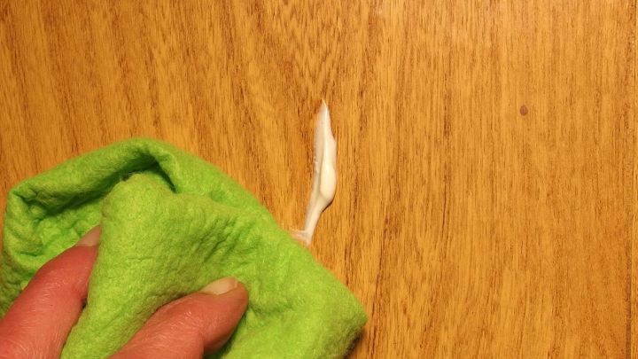 Eine gr&uuml;ne Reinigungstuch wischt &uuml;ber einen Holzstuhltisch, w&auml;hrend eine gl&auml;nzende M&ouml;belpolitur aufgetragen wird.