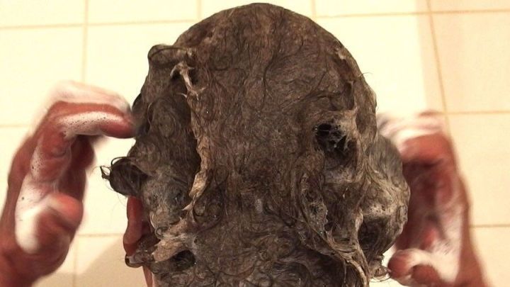 Ein Kopf wird in der Dusche mit Shampoo gewaschen, w&auml;hrend die H&auml;nde durch die Haare gleiten. Fettige Kopfhaut und trockene Spitzen sind deutlich zu erkennen.
