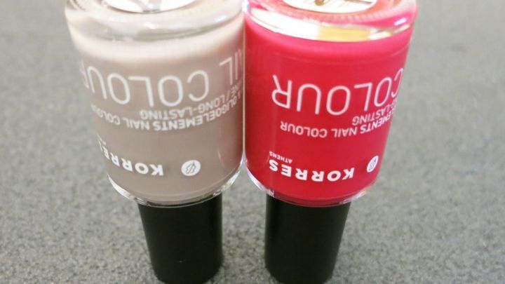 Zwei Nagellackflaschen stehen nebeneinander auf einer Oberfl&auml;che, eine beige und eine rote, beide bereit zur Anwendung.