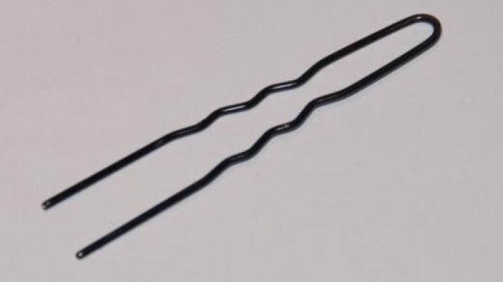 Ein schwarzer, gefalteter Draht bildet zwei Spitzen. Ruhend auf wei&szlig;em Hintergrund dient er m&ouml;glicherweise zum Kirschen entsteinen.