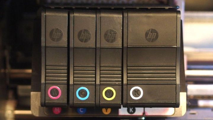 Tintenpatronen in einem Drucker, sortiert nach Farben (Magenta, Cyan, Gelb, Schwarz) und markiert mit entsprechenden Symbolen.
