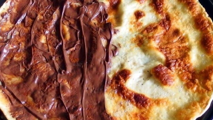 Zwei Crepes liegen nebeneinander, einer mit schokoladiger Creme bestrichen, der andere goldbraun und ohne Belag.