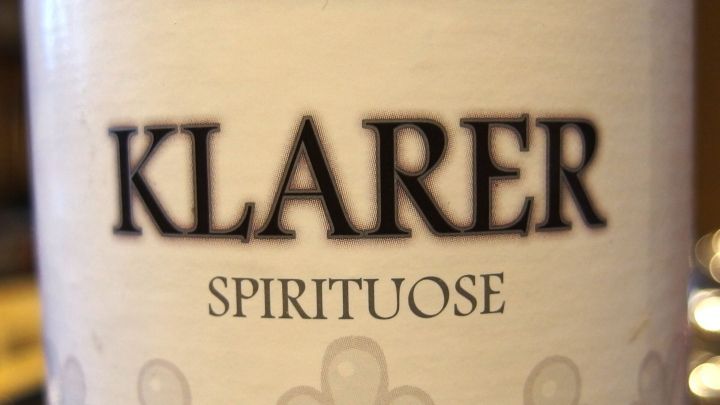 Ein klarer Spirituose-Flasche steht in einem leicht verschwommenen Hintergrund, geeignet zum Vermeiden von Katern.