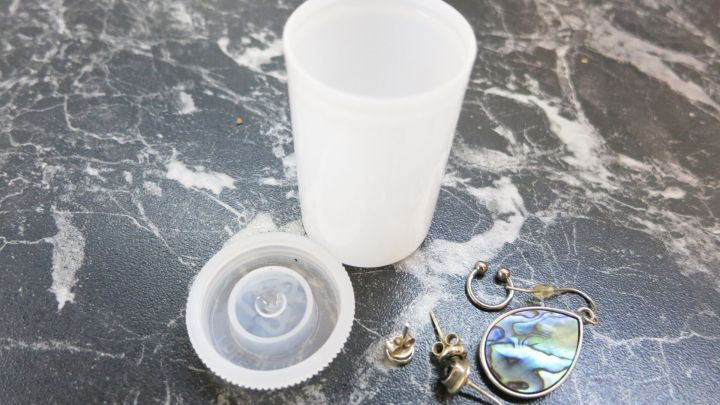 Ein auf einem Tisch liegendes Beh&auml;ltnis mit kaputten Ohringen, bereit zur sicheren Aufbewahrung.