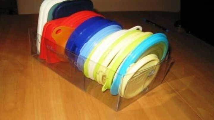 Plastikdeckel sind farblich sortiert in einer klaren Box auf einem Tisch. Eine ordentliche Anordnung zeigt Organisation.