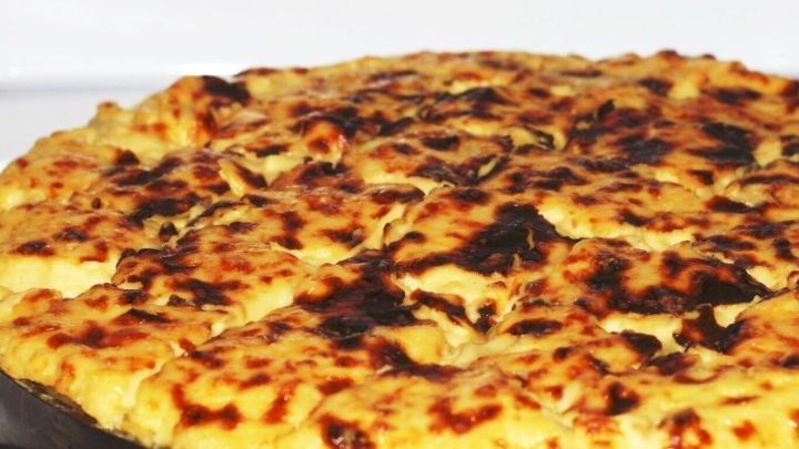 Ein verbrannter Auflauf liegt auf einem Blech, mit einer knusprigen, dunklen Kruste und hellem, weichem Innenleben.